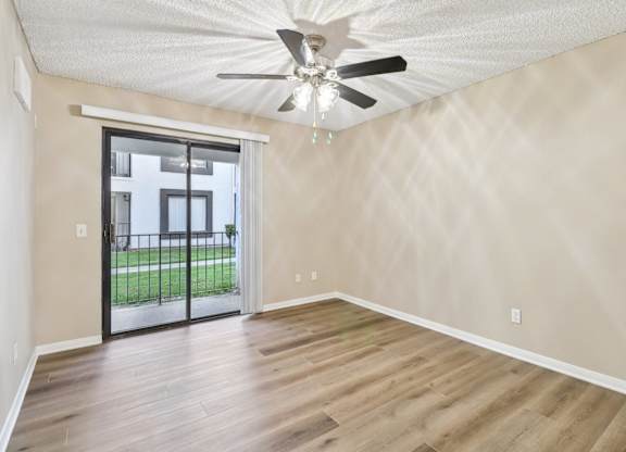 A room with a ceiling fan and sliding glass doors.