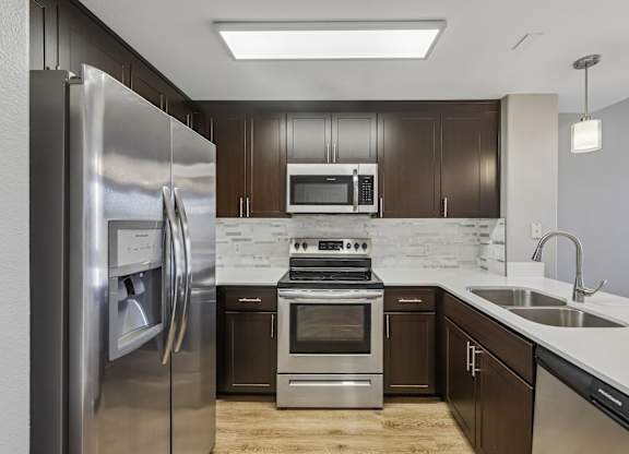 A modern kitchen with dark brown cabinets and stainless steel appliances.