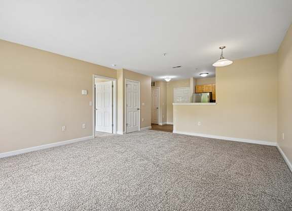 A large, empty room with carpeted flooring and white walls.
