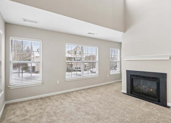A living room with a fireplace and three windows.