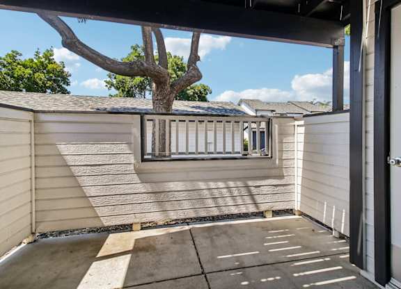 A patio area with a tree and a view of the sky.