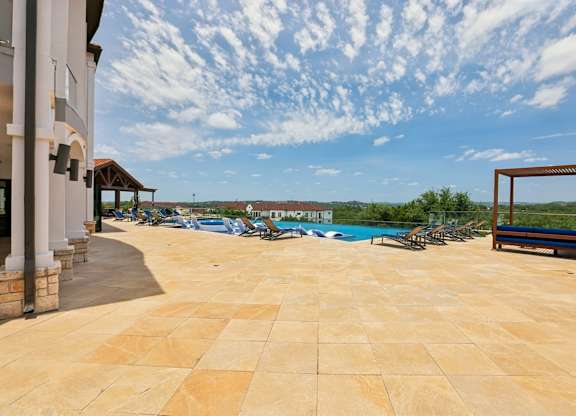 A patio with a pool and a bench.