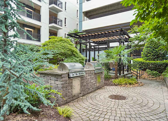 A small garden with a circular brick walkway and a small fountain in the middle.