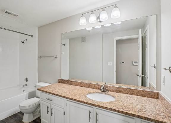 A bathroom with a granite countertop and a large mirror.