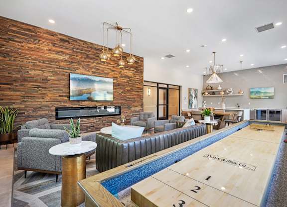 A shuffleboard table is in the middle of a room with a couch and a television.