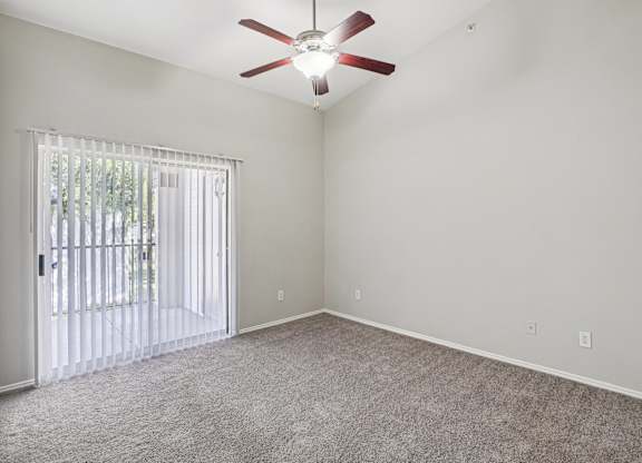 A room with a ceiling fan and a sliding glass door.