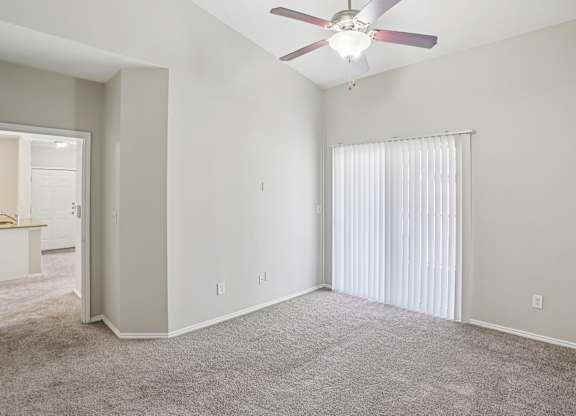 A room with a ceiling fan and carpeted floor.