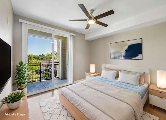 A bedroom with a bed, a ceiling fan, and a painting on the wall.