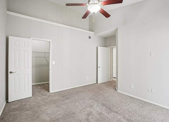 A room with a ceiling fan and carpeted floor.