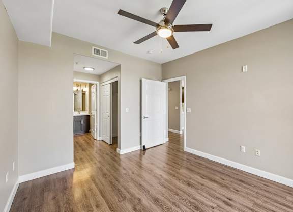 A room with a ceiling fan and wooden flooring.