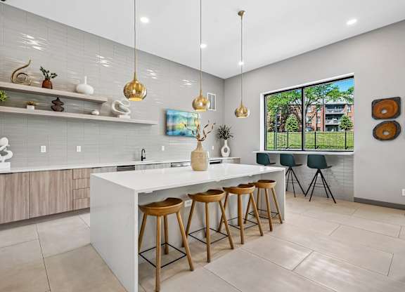 A modern kitchen with a white island and wooden stools.