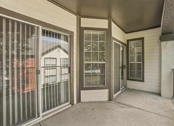 A patio with a sliding glass door and a metal railing.