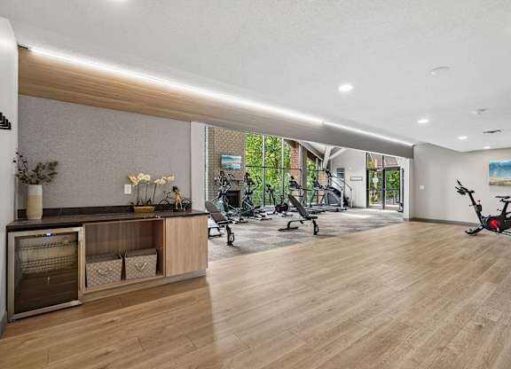 A spacious room with wooden floors and a variety of exercise equipment.