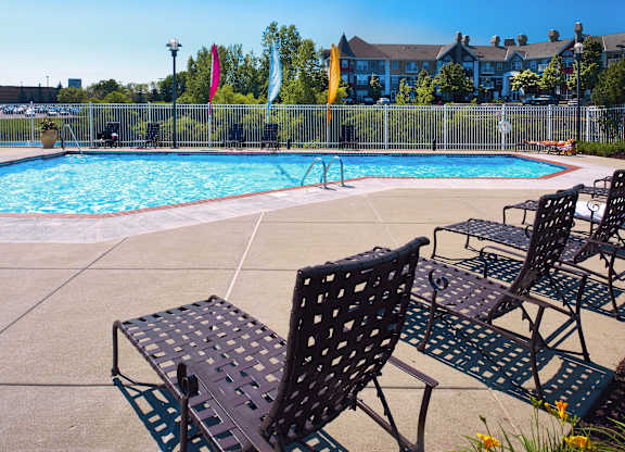 a swimming pool with patio furniture and chairs next to it