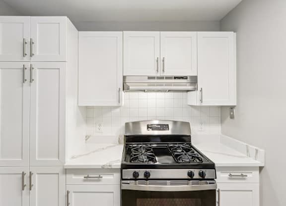 A modern kitchen with white cabinets and a stove top oven.
