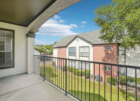 A balcony with a black railing and a view of a red brick house.