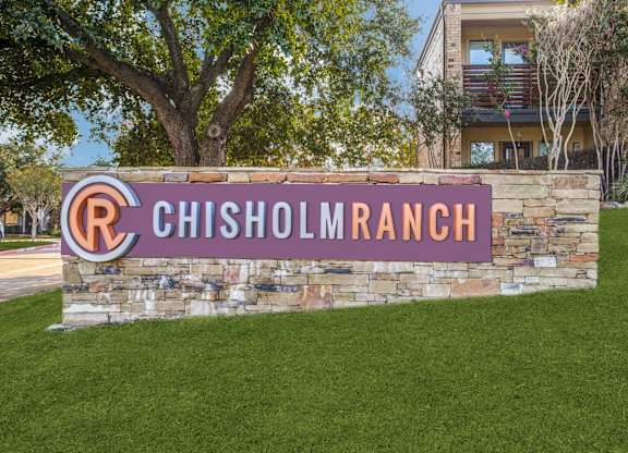 A sign that says Chisholm Ranch in front of a building.