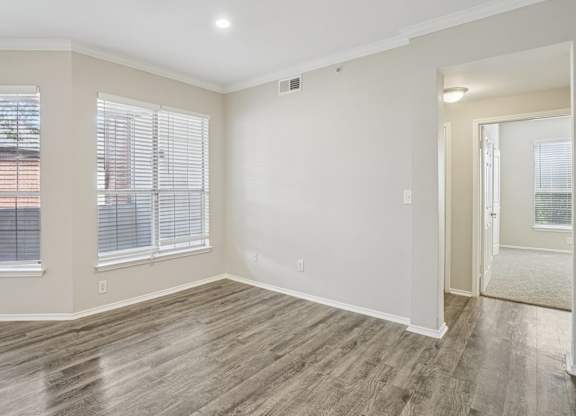 A room with wooden flooring and a window with blinds.