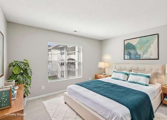A bedroom with a large bed and a painting on the wall.