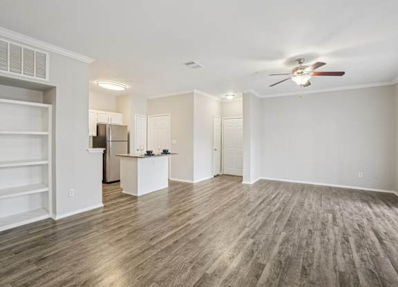 A spacious room with a ceiling fan and wooden flooring.