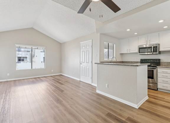 A kitchen with white cabinets and a wooden floor.