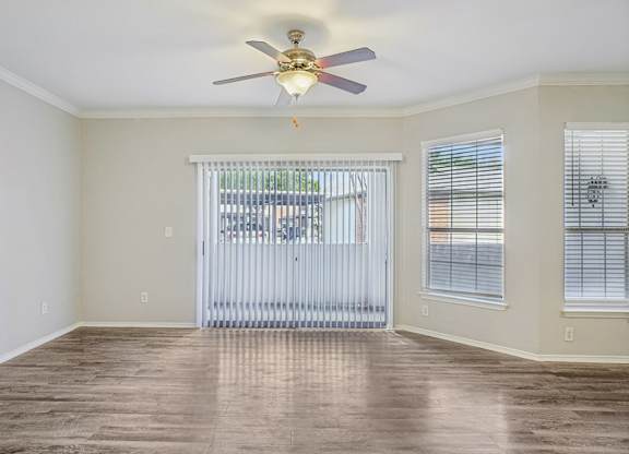 A room with a ceiling fan and sliding glass doors.