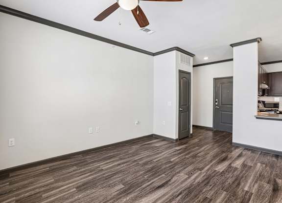 A room with a ceiling fan and wood flooring.
