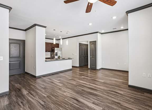 A room with a ceiling fan and wooden flooring.