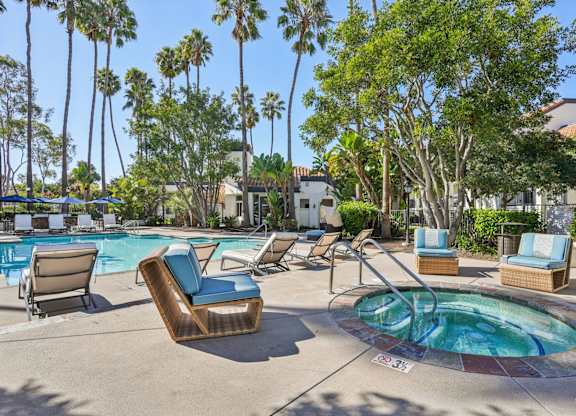A pool area with a hot tub and lounge chairs.