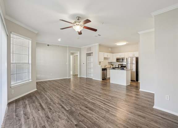 A spacious living room with a ceiling fan and hardwood flooring.