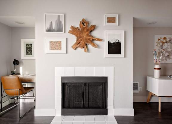 A fireplace with a leaf decoration above it and pictures on the wall.