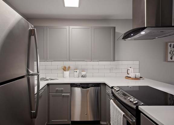 Apartments for Rent in Mountain Park - MiLO at Mountain Park - Chef-Grade Kitchen, with White Countertops and Backsplash, Grey Cabinetry, Black Electric Stovetop, and a Refrigerator.