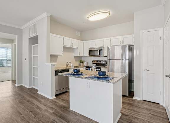 A kitchen with white cabinets and a wooden floor.