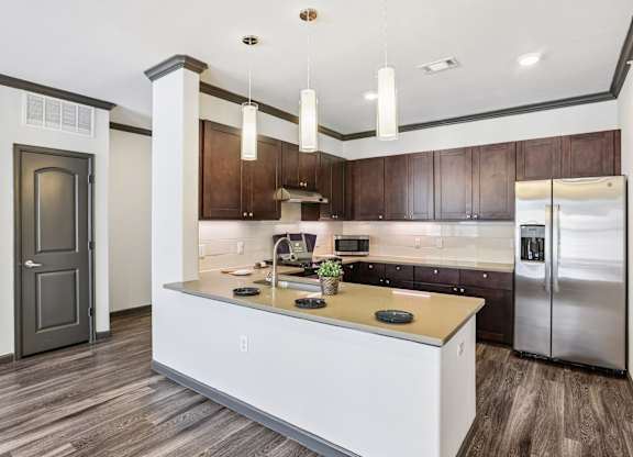 A modern kitchen with a white island and dark wood cabinets.