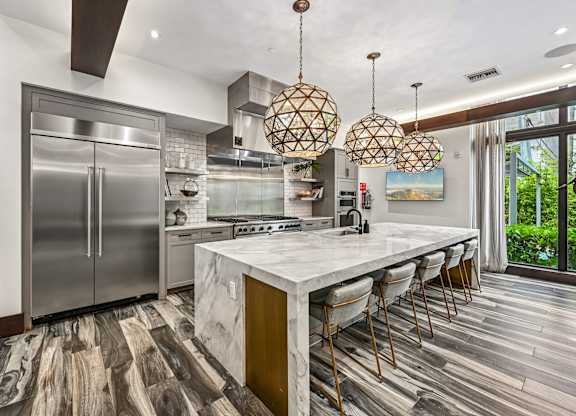 A modern kitchen with a marble countertop and stainless steel appliances.