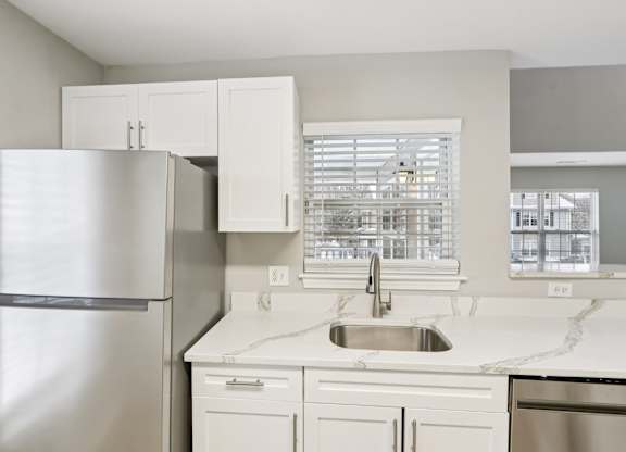 A kitchen with a stainless steel refrigerator and white cabinets.