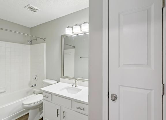 A white bathroom with a toilet, sink, and mirror.