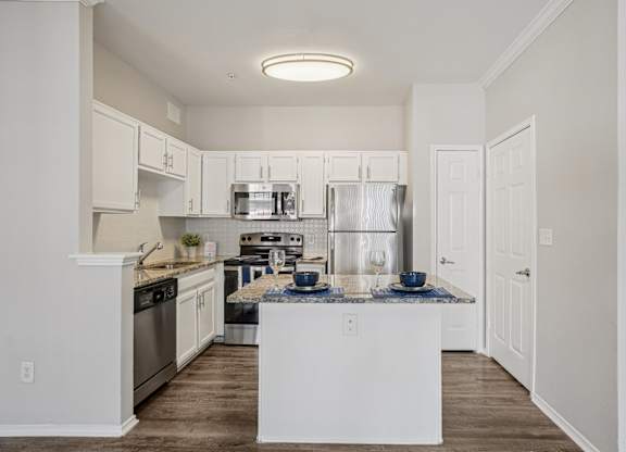 A kitchen with white cabinets and a white island.