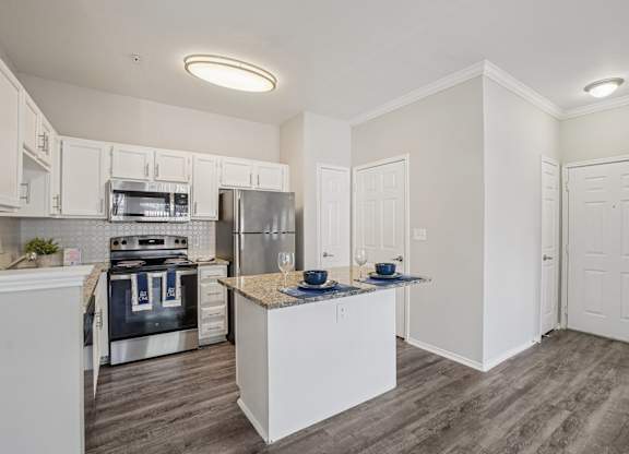 A kitchen with white cabinets and a wooden island.