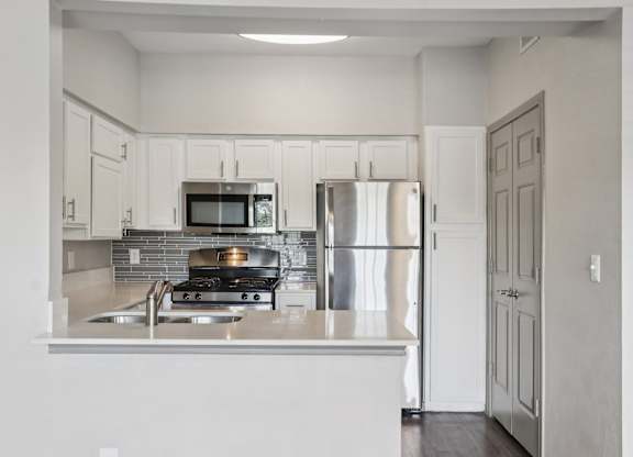 A kitchen with a stove, refrigerator, and microwave.