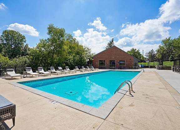 A large swimming pool surrounded by lounge chairs and trees.