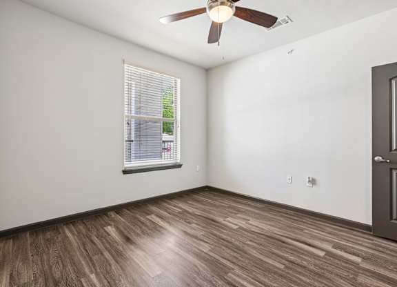 A room with a ceiling fan and a window with blinds.