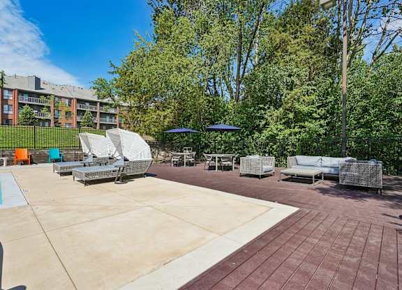 A sunny day at the outdoor seating area of a building with a pool and lounge chairs.