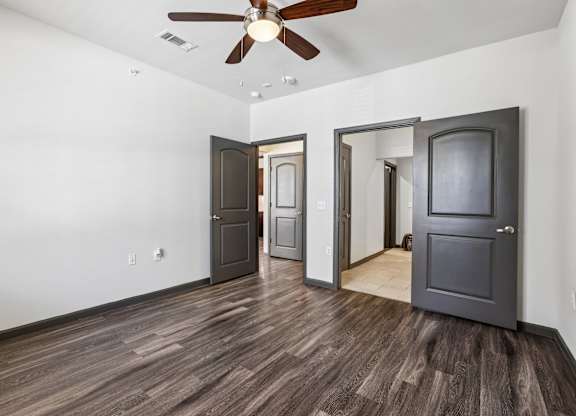 A room with a ceiling fan and wooden flooring.