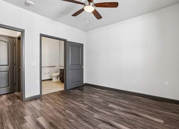 A room with a ceiling fan and wooden flooring.