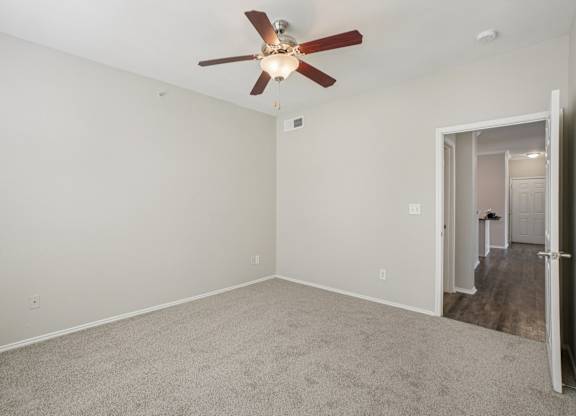 A room with a ceiling fan and carpeted floor.