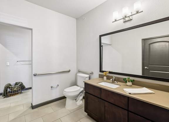 A bathroom with a toilet, sink, and mirror.