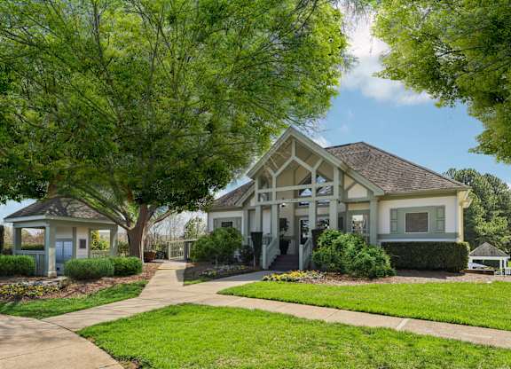 A house with a blue door and a porch is surrounded by greenery.