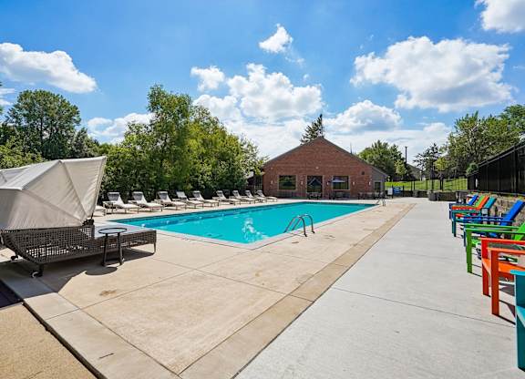 A pool area with a small building and lounge chairs.