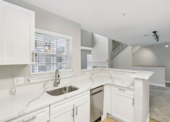 A kitchen with white cabinets and a marble countertop.